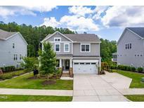 Charming two-story home featuring a manicured lawn, a two-car garage, and a welcoming front porch at 113 Hidden Bluff Dr, Chapel Hill, NC 27517