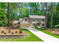 Charming two-story home with neutral siding, attached garage, and long driveway surrounded by lush trees at 11817 Coachmans Way, Raleigh, NC 27614