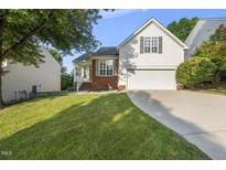 Charming home with a well-manicured lawn, two car garage, and a mix of brick and siding at 12505 Garden Tree Ln, Raleigh, NC 27614