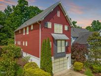View of the exterior of a red two-story home with an attached garage and beautiful landscaping at 129 Ruskin Dr, Chapel Hill, NC 27516
