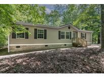 Charming single-story home featuring vinyl siding, black shutters, and a wooden porch nestled in a lush wooded setting at 130 S Creek Dr, Louisburg, NC 27549