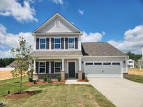 Charming two-story home with gray siding, black shutters, and a two-car garage under a clear blue sky at 142 Benson Village Dr # 82, Benson, NC 27504