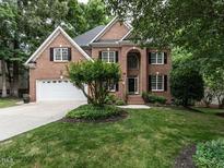 Charming two-story brick home featuring a well-manicured lawn, attached garage, and professionally landscaped front yard at 203 Chilcott Ln, Apex, NC 27502