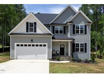 Charming two-story home with gray siding, black shutters, covered porch, and a spacious two-car garage at 220 Purslane Dr, Franklinton, NC 27525