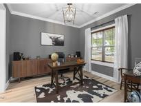 A home office boasts hardwood floors, gray walls, a natural wood desk, and a decorative black and white cowhide rug at 220 Purslane Dr, Franklinton, NC 27525