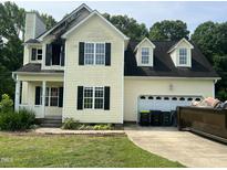 Two-story yellow home with black shutters, attached garage, and visible fire damage near the front left upper window at 2377 Vinson Rd, Clayton, NC 27527