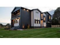 Modern home featuring a striking dark and light exterior, professional landscaping, and outdoor lighting at 500 Grigsby Ave, Holly Springs, NC 27540