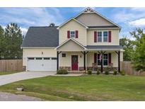 Charming two-story home featuring a red door and shutters, a well-manicured lawn, and an attached two-car garage at 576 Prairie Ln, Lillington, NC 27546