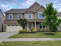 Two-story home featuring a manicured lawn, attached garage, and charming front porch at 617 Hiddenbrook Dr, Durham, NC 27703