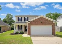 Charming two-story home with a brick and vinyl facade, a well-manicured lawn, and an attached two-car garage at 634 Cotton Brook Dr, Fuquay Varina, NC 27526