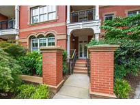 Charming brick building entrance featuring a covered porch, stone pillars, and landscaped greenery at 710 Independence Pl # 103, Raleigh, NC 27603