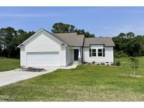 Inviting new construction features a light exterior, attached garage and a neatly landscaped front yard at 81 Coharie Dr, Lillington, NC 27546