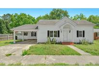 Charming white home featuring a covered carport, dark shutters, and a well-manicured front yard at 102 S College Ave, Kenly, NC 27542