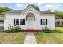 Charming white home featuring a brick-lined walkway and meticulously manicured landscaping at 102 S College Ave, Kenly, NC 27542