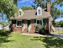 Charming brick home featuring dormer windows, a green door, and lush green landscaping at 1305 Shakentown St, Knightdale, NC 27545