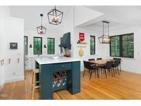 Bright kitchen with white cabinets, a contrasting emerald island, and a dining area with hardwood floors at 1503 Hollywood St, Durham, NC 27701