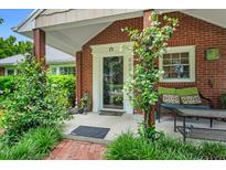 Inviting front porch with brick accents, cozy seating, and lush landscaping at 202 Hilltop Ave, Garner, NC 27529