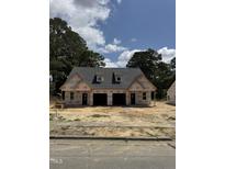 Under construction new home with garage doors and protective wrap under a sunny, partly cloudy sky at 203 S Main St # A, Four Oaks, NC 27524