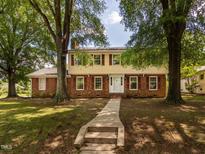 Traditional two-story home with red brick and yellow siding, surrounded by mature trees at 223 Shadowbrook Dr, Burlington, NC 27215