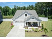 Charming home with a well-manicured lawn, American flag, and a covered porch for relaxing at 2501 Impulsion Dr, New Hill, NC 27562