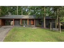 Charming, single-story home with dark exterior paint, bright trim, a level lawn and mature shade trees at 307 Yowland Rd, Henderson, NC 27536