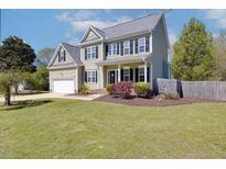Charming two-story home with a well-manicured lawn, attached garage, and inviting front porch at 3208 Wilbon Ridge Dr, Holly Springs, NC 27540