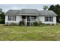 A single-story house with a sloped roof and small front porch in need of maintenance and landscaping at 3213 Sam Usry Rd, Oxford, NC 27565