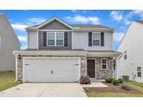 Two-story home with a two-car garage, stone accents, and vinyl siding for a modern look at 717 Little Patch St, Zebulon, NC 27597