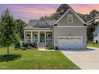 Charming home boasts a well-manicured lawn, a welcoming front porch, and an attached two-car garage at 816 Trumpet Vine Ct, Wendell, NC 27591