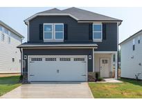 Two-story home with dark siding, a white garage door, and a small front yard at 845 Ottawa Dr, Garner, NC 27529
