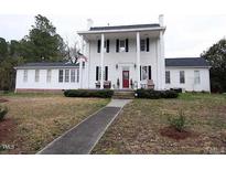 Charming two-story white home featuring a traditional front porch and manicured lawn at 100 Lager Ln, Garner, NC 27529