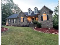 Charming brick home with dormers, manicured lawn, and landscape lighting at 1016 Luminary Ln, Willow Springs, NC 27592