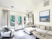 Bright living room with a white sectional sofa and French doors to the outdoor deck at 107 Long Shadow Ln, Cary, NC 27518