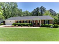 Charming brick home featuring lush green lawn, manicured hedges and a bright red front door at 1206 Ivy Ln, Raleigh, NC 27609