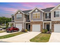 Townhome exterior with neutral siding, brick accents, individual driveways, and attached garages at 1230 Adrian Ct, Mebane, NC 27302