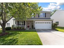 Charming two-story home with a well-manicured lawn, mature tree, and a welcoming front porch at 12417 Kendall Ridge Ct, Durham, NC 27703