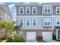 Stylish townhome featuring a brick facade, two-car garage, and neutral-toned siding for a modern look at 217 Jones Hill Rd, Holly Springs, NC 27540