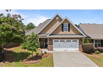 Charming home featuring a two-car garage, stone accents, manicured lawn, and mature trees under a sunny blue sky at 232 Shady Hollow Ln, Garner, NC 27529
