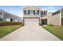 Charming two-story home features a two-car garage, stone accents, and well-manicured lawn at 2406 Lily Dr, Haw River, NC 27258