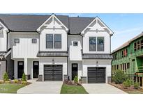 Modern townhome showcasing white siding, black framed windows and doors, and individual garages at 3908 Lost Fawn Ct, Raleigh, NC 27612