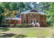 Traditional brick home with a landscaped front yard and inviting entrance with charming front lawn and mature trees at 5304 W Oaks Dr, Fuquay Varina, NC 27526