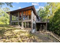 Rustic home featuring large windows, a deck, and lush greenery, creating a serene and inviting atmosphere at 5900 Ebenezer Church Rd, Raleigh, NC 27612