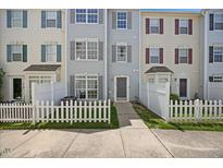Charming townhouse featuring a welcoming entrance, well-maintained lawn, and classic white picket fence at 8630 Neuse Landing # 105, Raleigh, NC 27616