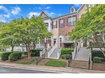 Charming townhomes with brick and siding exteriors, manicured landscaping, and inviting stairways leading to covered entryways at 9211 Calabria Dr # 104, Raleigh, NC 27617