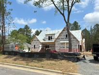 New construction home featuring wood framing, protective wraps, and a modern design with lush greenery surroundings at 93 Bur Oak Ct, Pittsboro, NC 27312