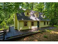 Inviting two-story home with a charming yellow exterior and spacious deck, nestled among lush green trees at 106 Redbud, Pittsboro, NC 27312