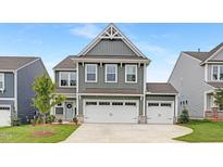 Charming two-story home featuring a three car garage, manicured lawn, and modern architectural details at 140 Summer Mist Ln # 159, Clayton, NC 27527