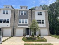 Modern townhome featuring brick, white, and gray facade, complemented by individual garages and well-manicured landscaping at 1900 Fishamble St # 17, Fuquay Varina, NC 27526