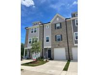 Modern townhome featuring brick and gray siding, garage, and well-maintained landscaping under a bright blue sky at 1924 Fishamble # 23, Fuquay Varina, NC 27526