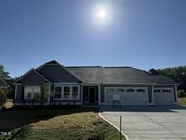 New home showing a charming gray facade, three car garage, and well maintained lawn at 240 Eason Creek Way, Clayton, NC 27527